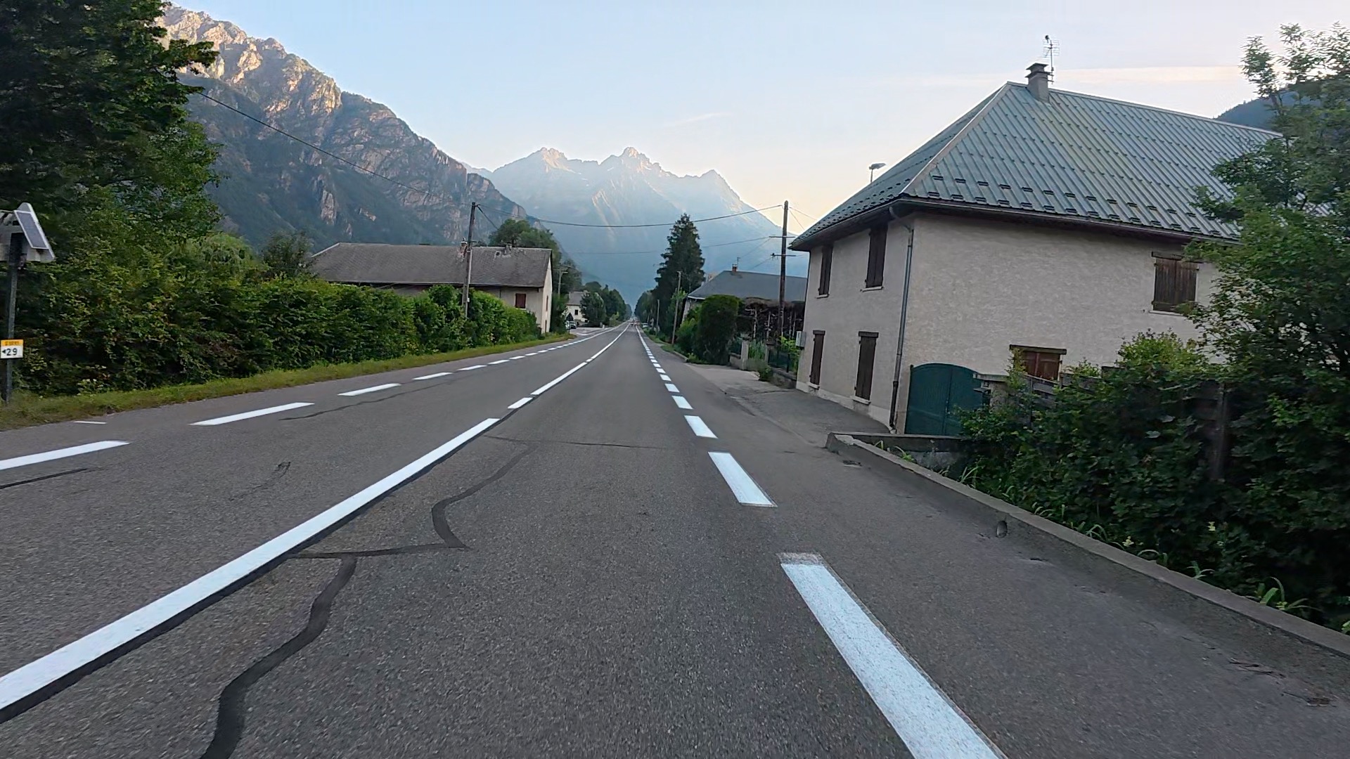 Long empty road out of Bourg d'Oisans with Alpes in distance. Horsham Cycling.